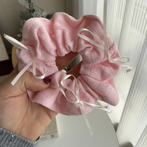 Detailed macro shot of pink knit hair scrunchie with delicate white ribbon bows
