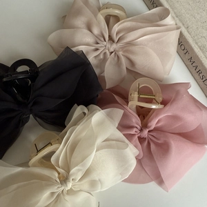Detail of elegant chiffon bow hair claws in beige, black, pink, and cream colors