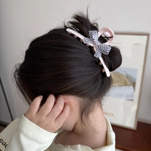 Vue détaillée d'une pince à cheveux rose à pois avec nœud pour chignon élégant
