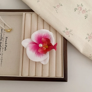 Détail de la pince à cheveux orchidée dégradé rose avec perle centrale sur plateau