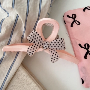 Détail de la pince à cheveux rose avec un nœud transparent à pois noirs élégant