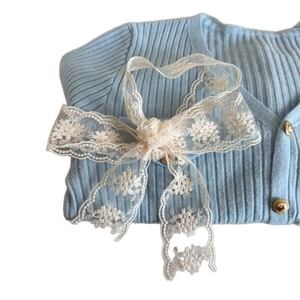 Light blue knit cardigan with gold buttons and floral white lace bow decoration