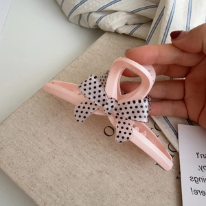 Pince à cheveux rose avec nœud et motifs à pois noirs et blancs pour un style élégant