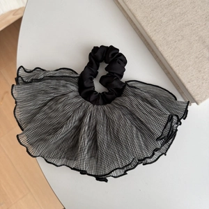 Vue détaillée d'un chouchou à carreaux vichy noir et blanc avec bords volantés