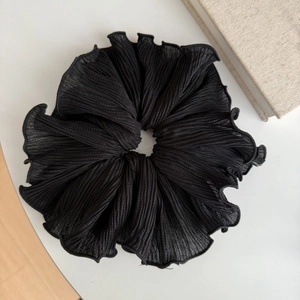Détail d'un chouchou noir à motif pied-de-poule avec plis accordéon et bords à volants
