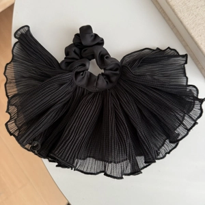 Détail d'un chouchou en tissu plissé noir avec une texture ondulée unique et chic