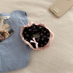 Gros plan d'un chouchou à imprimé nœud rose avec bords en dentelle et ruban soyeux