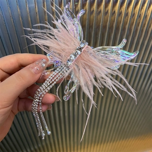 Macro detail of butterfly hair clip with pink feathers and long rhinestone tassels