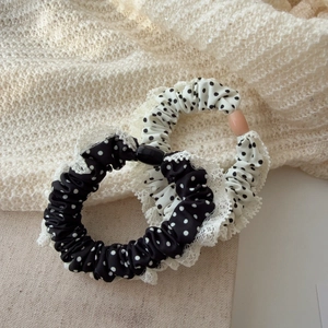 Détail des chouchous en dentelle à pois avec perles blanches sur un fond en tissu texturé