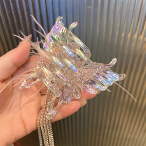 Close-up of holographic butterfly hair claw with pink feathers and rhinestone tassels