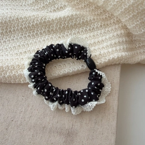 Gros plan sur un chouchou à pois noirs et blancs avec bordure en dentelle