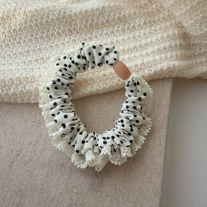 Détail du chouchou blanc à pois avec bordure en dentelle et ornement rose rectangulaire