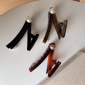 Close-up of geometric zigzag hair claws in black, brown and amber with pearl details