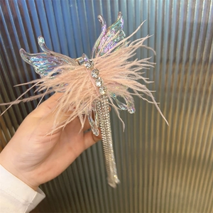 Detail of pink feather hair clip with iridescent butterfly wings and rhinestone tassels