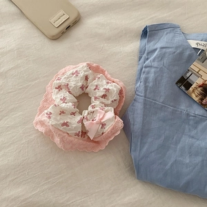 Chouchou en dentelle rose avec motifs nœuds rouges et ruban satiné sur tissu blanc doux