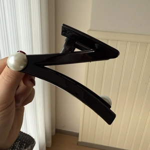 Close-up of black Z-shaped hair claw clip with large pearls and metallic spring details