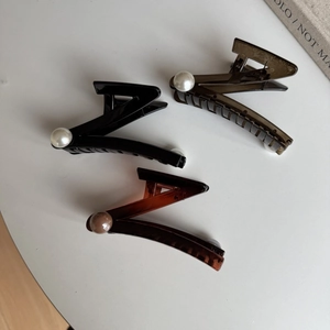 Detail of Z-shaped large hair claws with pearls in black, grey and amber colors