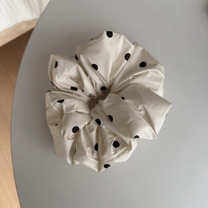 Vue détaillée d'un chouchou en soie à pois noirs avec une texture satinée et brillante