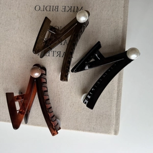 Three elegant pearl-studded hair claws in brown, black, and amber resin colors