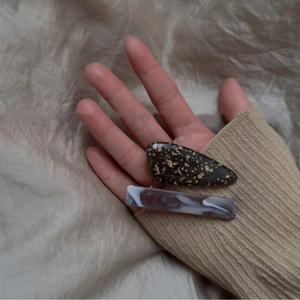 Close-up of acetic acid hair clips with gold foil marble texture and rectangle drop design