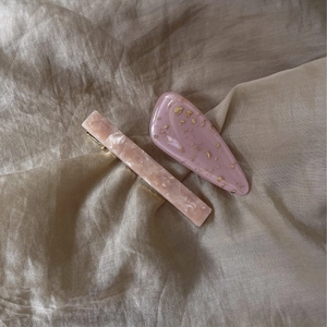 Close-up of pink marble acetate hair clips and gold leaf resin slide on champagne satin