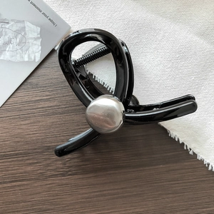 Dettaglio di un fermaglio per capelli nero con accento argento su una base di legno