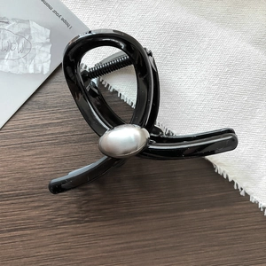 Dettaglio di un fermaglio per capelli nero con perla argento opaca dal design moderno