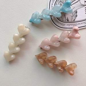Detail of four colorful resin heart hair clips with pearlescent and marble textures