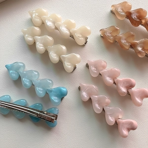 Detailed view of multi-colored heart hair clips with resin marble texture and metal base