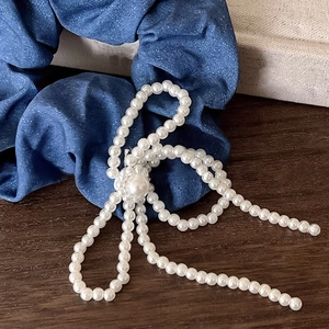 Chouchou en denim bleu orné d'un nœud en perles élégant sur un support en bois rustique