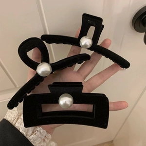 Detailed view of black velvet shark hair clips set featuring large pearl accents