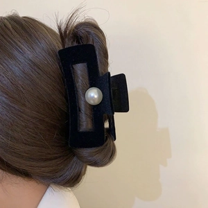 Detail of elegant black velvet hair claw clip with large pearl on a rectangular frame