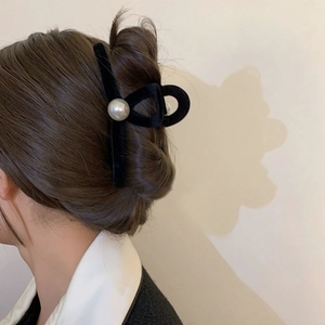 Close-up of black velvet hair claw clip with large pearl on a back-view model hairstyle