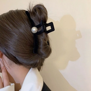Detail of a large black velvet hair claw clip with a white pearl on a model's hair