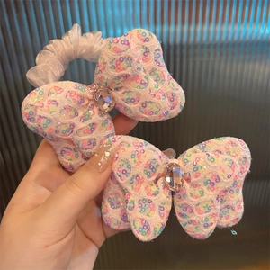 Détail d'un chouchou noeud rose à paillettes avec une pierre précieuse scintillante
