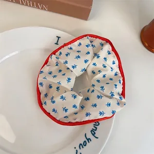 Chouchou à fleurs bleues avec bordure en satin rouge sur une assiette décorative blanche