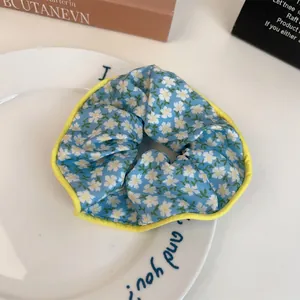 Gros plan détaillé d'un chouchou à fleurs avec tissu bleu et bordure cousue jaune
