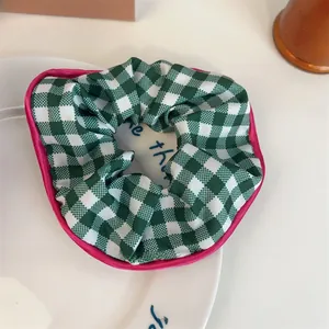 Détail macro d'un chouchou à carreaux verts avec bords en satin rose sur une assiette