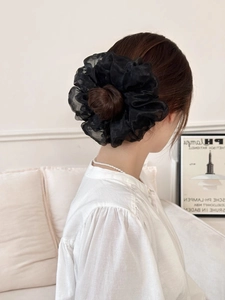 Dettaglio di un elegante elastico scrunchie nero in organza su uno chignon sofisticato