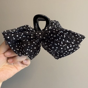 Detail of a French vintage black polka dot bow hair claw clip made of chiffon fabric