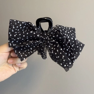 Detailed close-up of a black French polka dot organza bow hair claw clip accessory