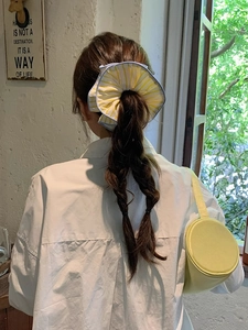 Detail of yellow striped oversized hair scrunchie with blue piping on a model