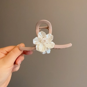 Detalle de la pinza para el cabello rosa palo con una elegante flor de resina blanca grande