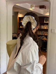Detail of yellow and white striped oversized scrunchie worn on a bun hairstyle
