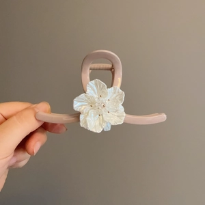 Detalle de pinza para el cabello rosa mate con flor blanca en 3D y adornos de perlas