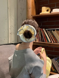 Detail showing oversized yellow striped hair scrunchie with blue ruffle edge on bun