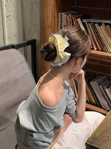 Detail of oversized yellow striped scrunchie with blue edging on a messy bun hairstyle