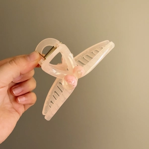 Pink translucent wheat ear hair claw clip with pink beads held by a hand