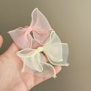 Close-up of pink and beige organza hair bows featuring fine stitched wavy edge details