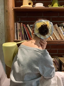 Detail of yellow striped fabric oversized scrunchie styled on a bun with a casual outfit